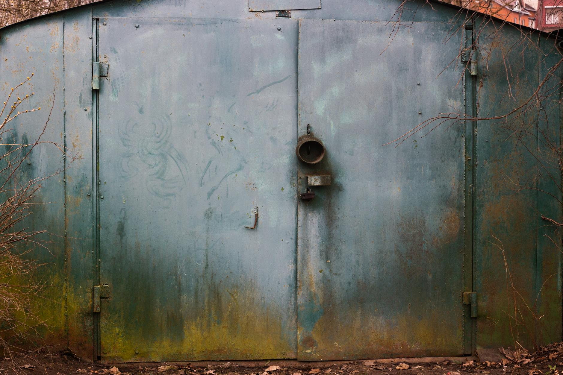 A weathered metal door with a rustic patina, surrounded by natural elements. Perfect for backgrounds or textures.